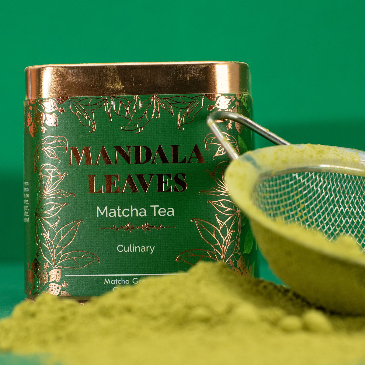 Grüner Matcha-Pulverhaufen vor einer Dose mit der Aufschrift 'Matcha Tee Kulinarisch' und einem Sieb im Hintergrund.